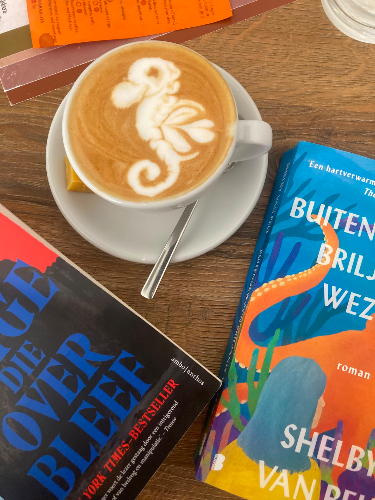 Latte art naast twee romans van de boekenclub