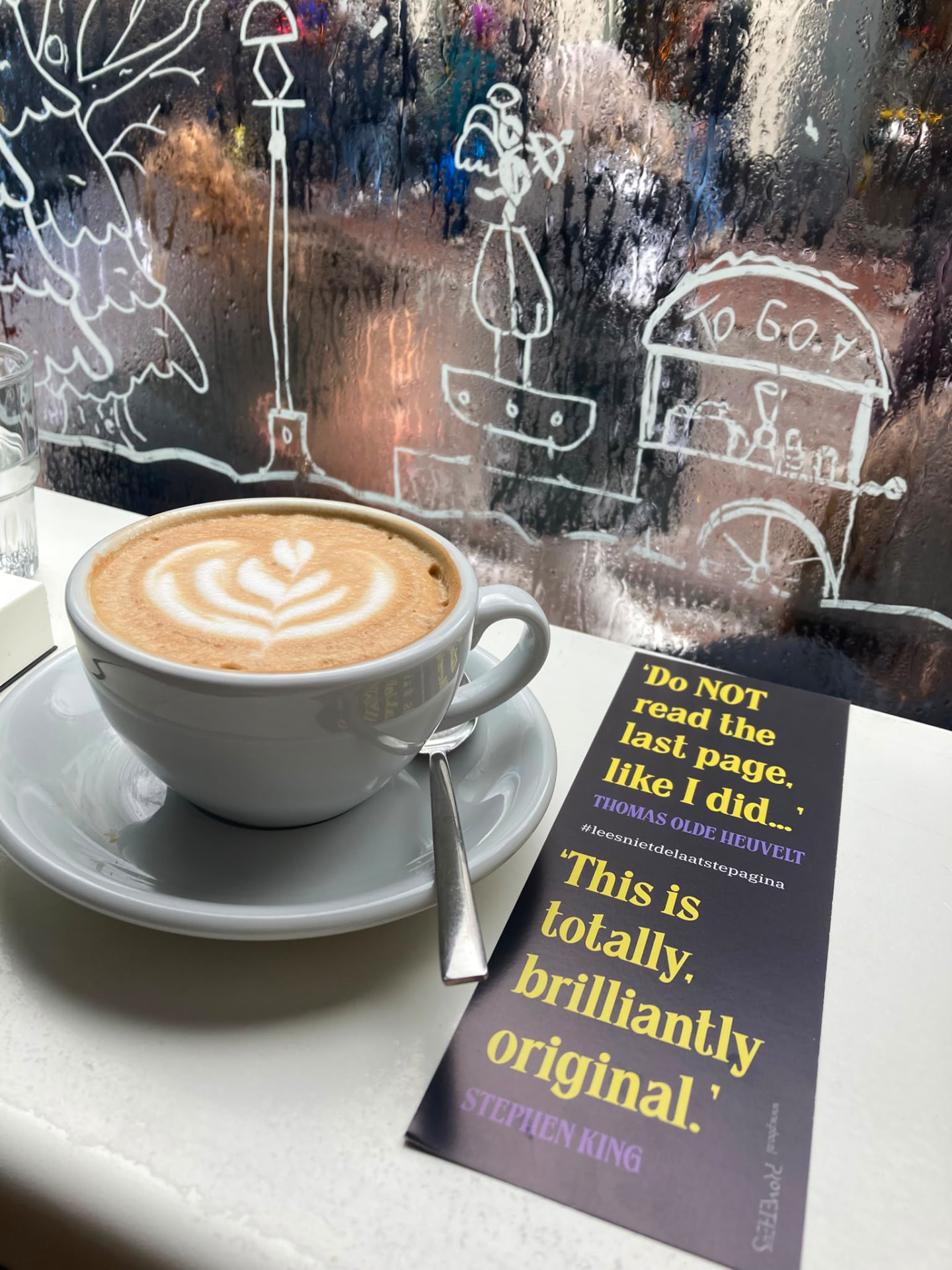 Cappuccino met een boekenlegger op tafel